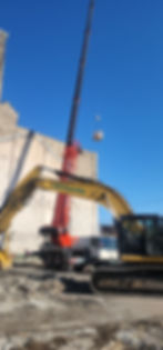 excavator and high reach wrecking a warehouse building