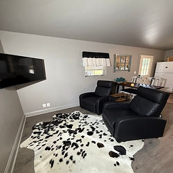 Two recliners and cow skin rug in area to watch tv