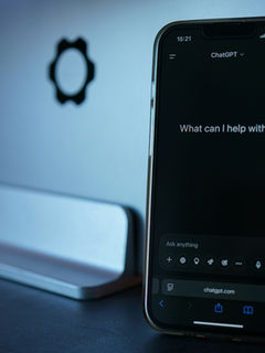 Smartphone displaying ChatGPT beside a laptop on a desk