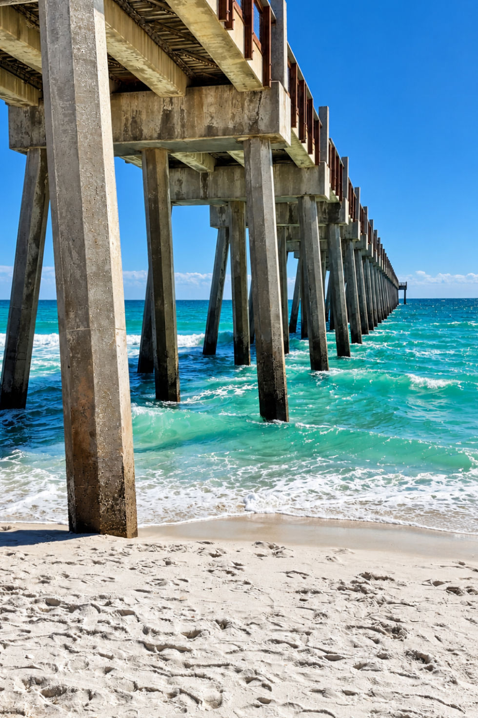 Pier stretching over turquoise Gulf water and white sand beach in Pensacola, Florida.