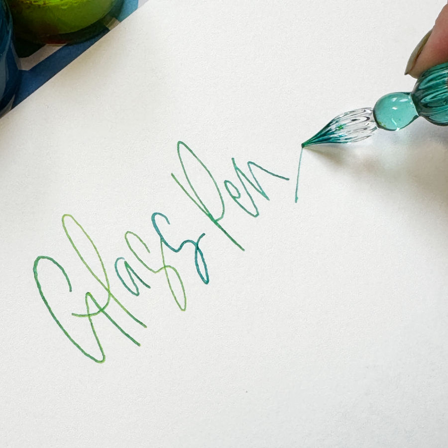 Thumbnail: glass dip pens captured beside flowing monoline hand-lettered script, showing their use in modern calligraphy.