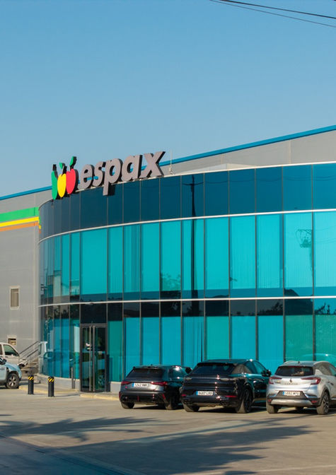Fachada de la empresa Espax con ventanales azules y coches estacionados