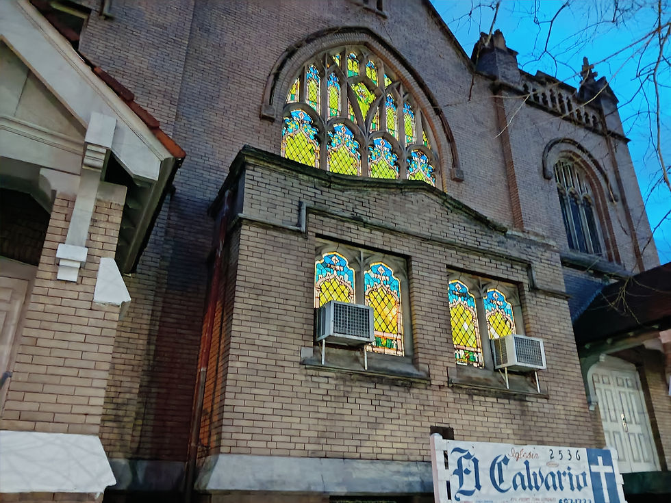 Evening view of Iglesia Pentecostal El Calvario in Cleveland, showing illuminated stained glass windows and part of the church’s sign at the entrance.