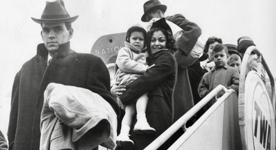 Cuban refugee families in coats and hats step off a TWA airplane at Cleveland Hopkins Airport on February 28, 1962, arriving through federal resettlement programs to start new lives after fleeing Cuba.