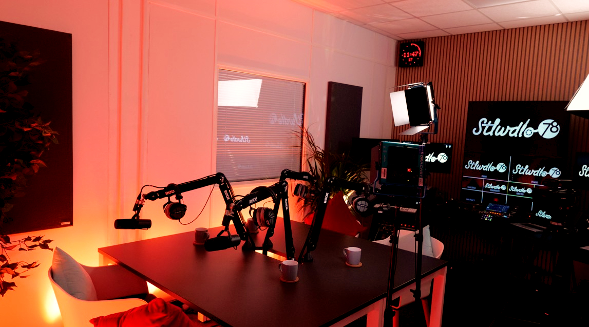 Stiwdio78's dressed podcast set with microphones, cameras, screens, seating and warm set lighting.