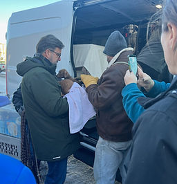 Animal rescue team transporting a dog from a vehicle during a winter intake, representing lifesaving rescue and community coordination