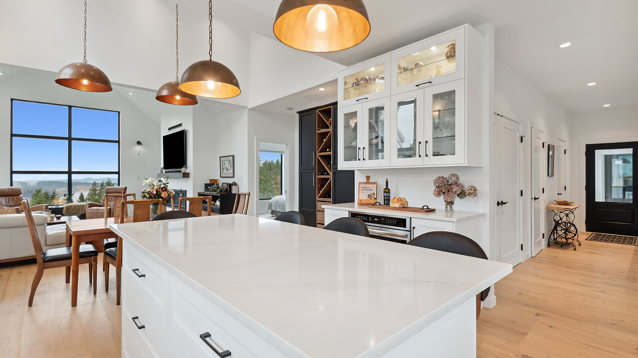 Open concept kitchen with white granite counter tops, Half glass cabinets with white borders and black pulls