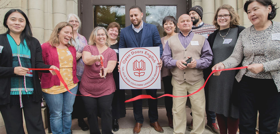 Founding members of Open Doors English stand in front of a building cutting a ribbon. Former Mayor Svante Myrick stands in the center holding a sign with the Open Doors English logo.