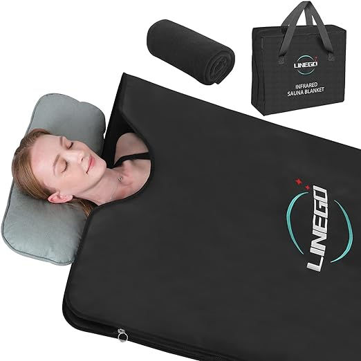 Woman with her eyes closed and a smile, laying inside of black, Linego sauna blanket