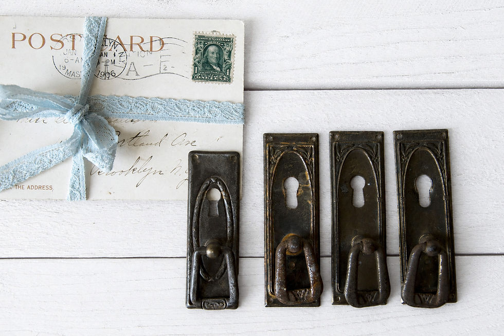 Three vintage portrait furniture handles with decorative metal backplates and keyholes, shown with an old postcard