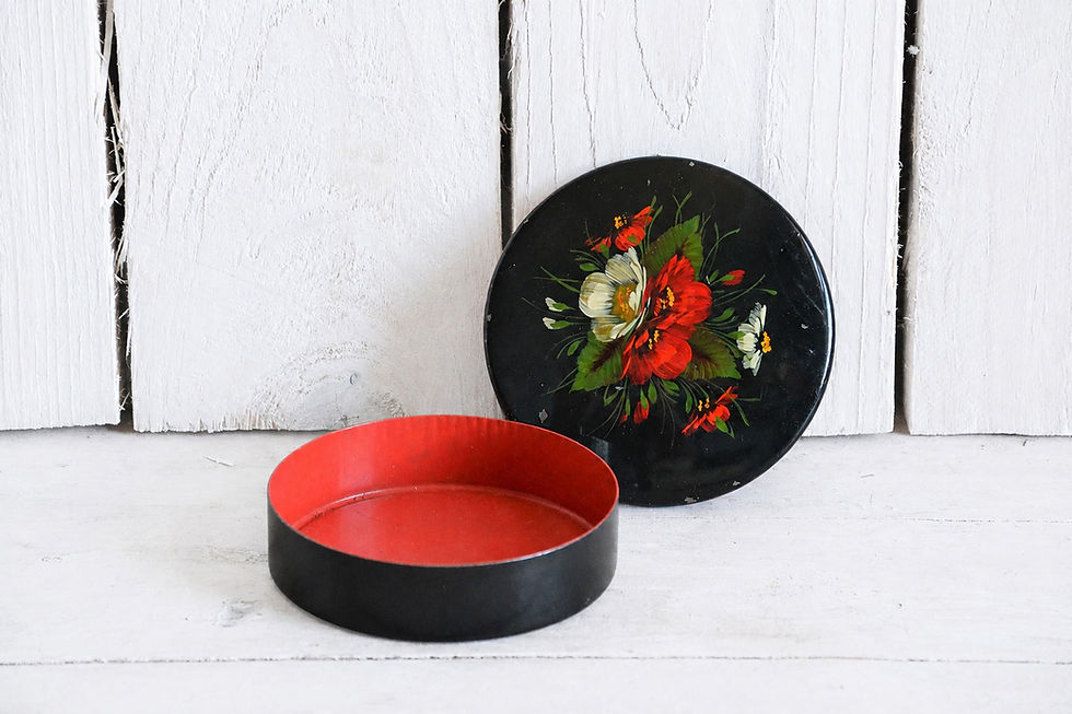 Vintage floral trinket box shown open with bright red interior, black exterior and painted flower lid standing behind
