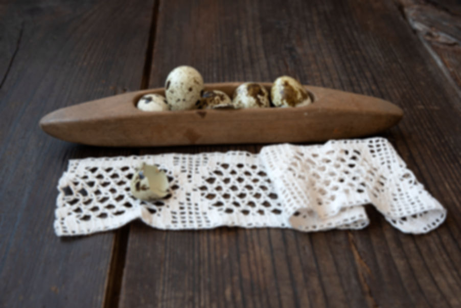 Timeworn wooden weaving shuttle with a warm aged tone on flax-colored cloth