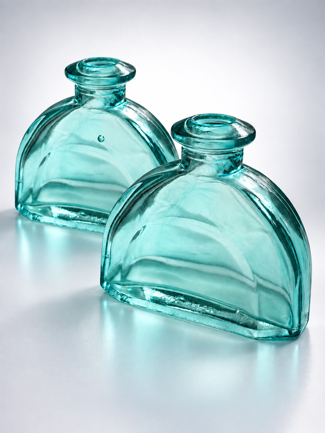Set of two vintage aqua blue-green glass bottles with low flattened shape and natural air bubbles