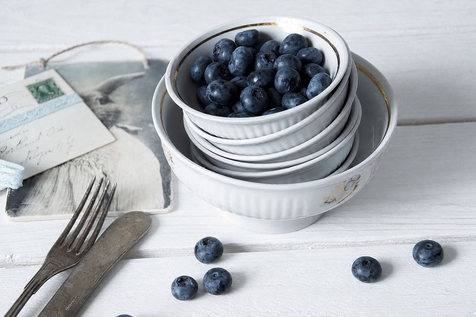Stack of vintage white ceramic bowls with gray floral decoration, styled with fresh blueberries and old letters