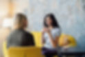 Clinical Therapist Supervision women discussing client across from each other yellow couch in modern brightly lit blue and yellow space