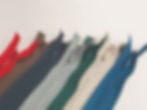 Blue thread spool on holder for industrial sewing machine with thread spools on wall rack in background