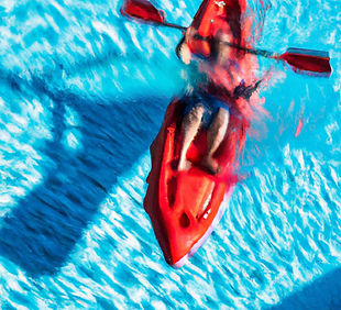Person in a red plastic sea kayak in a swimming pool doing a roll.jpg