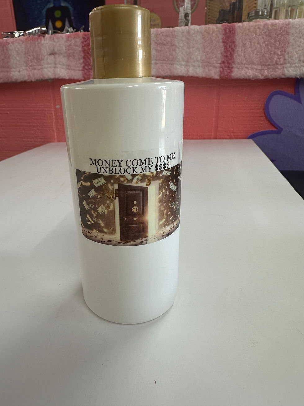 White bottle with gold cap reads: MONEY COME TO ME, product shot.