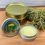 Thumbnail: Open tin of dandelion salve, with closed tins and herbs on wood