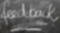 The word "feedback" is written in white chalk on a blackboard, with an underline emphasizing the text. The mood appears educational.