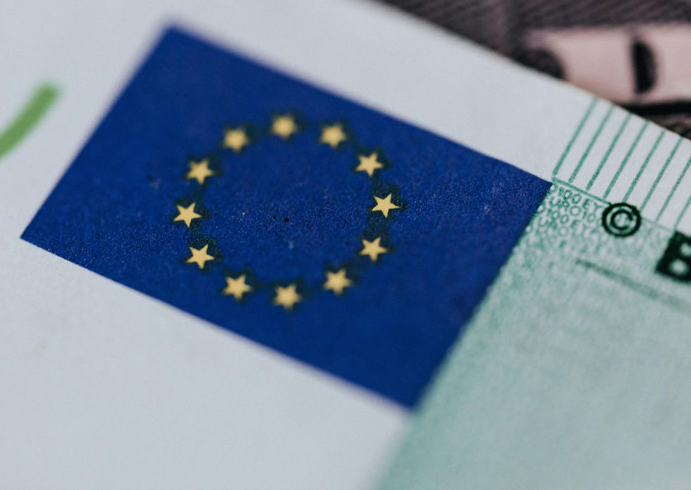 EU flag with yellow stars on a blue rectangle, part of a banknote. Close-up shows green text and patterns, suggesting currency detail.