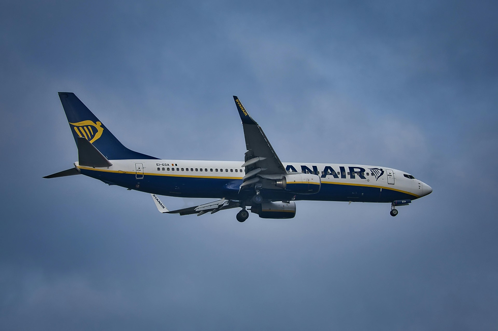 Blue and white Ryanair airplane in flight against a cloudy sky. The airline logo and text are visible on the fuselage and tail.
