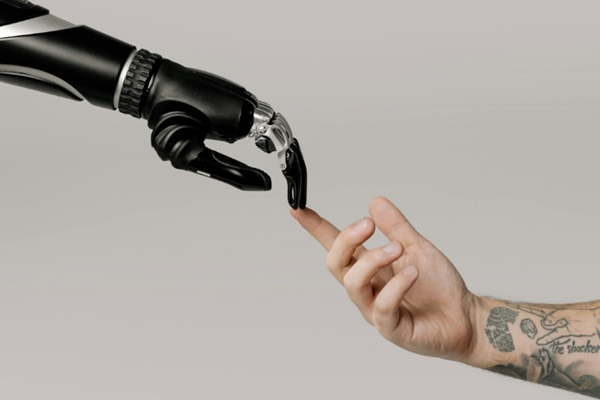 A robotic hand and a human hand touch fingers against a plain background, symbolizing a connection between technology and humanity.