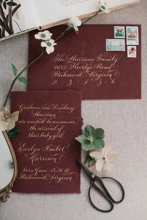 Handwritten full calligraphy birth announcement and envelope on Share Studios hand made paper. Gold ink on Burgundy paper