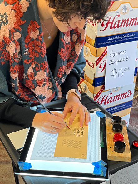 Close up of Emily Rose Cooper writing in calligraphy on a Maker's Mark label for a brand activation event