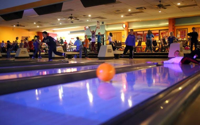 Orange bowling ball rolling down the bowling alley