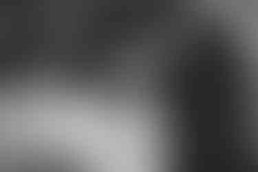 Chef in black chef's clothing carefully slicing vegetables in an industrial kitchen.