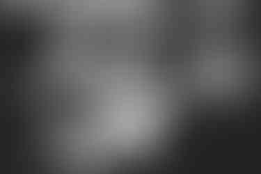 People seated around a table drinking and talking in a cozy, dimly lit setting with framed art on the walls. Black and white.