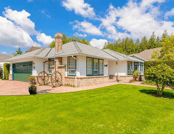 Well maintained ranch style home with garage and green lawn on a sunny day