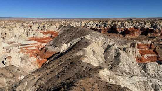 Expansive view across Ha Ho No Geh Canyon with striped hills and open desert