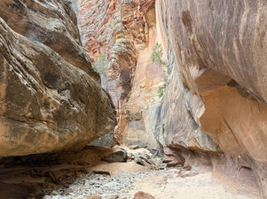 Tall canyon walls rising above a sandy wash with scattered rocks in Clear Creek