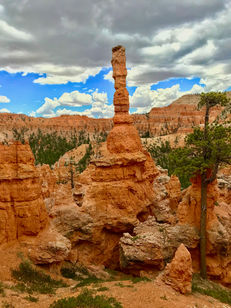 Tall, slender hoodoo spire against blue sky in Bryce Canyon