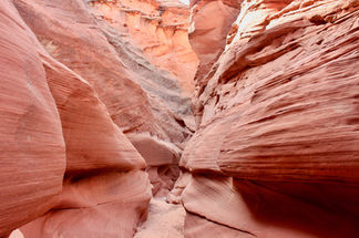Narrow slot canyon walls with layered red sandstone formations in Waterholes Canyon