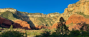 Wide view of Long Canyon walls with layered red rock cliffs under blue sky