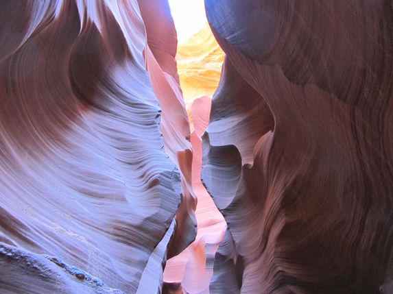 Curving slot canyon walls with layered textures in shades of red and purple