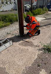 Telecommunications worker inspecting the base of a utility pole before climbing during pole stepping and overhead line safety training.