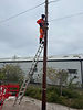 Telecommunications engineer installing overhead cabling during practical Openreach PIA training.