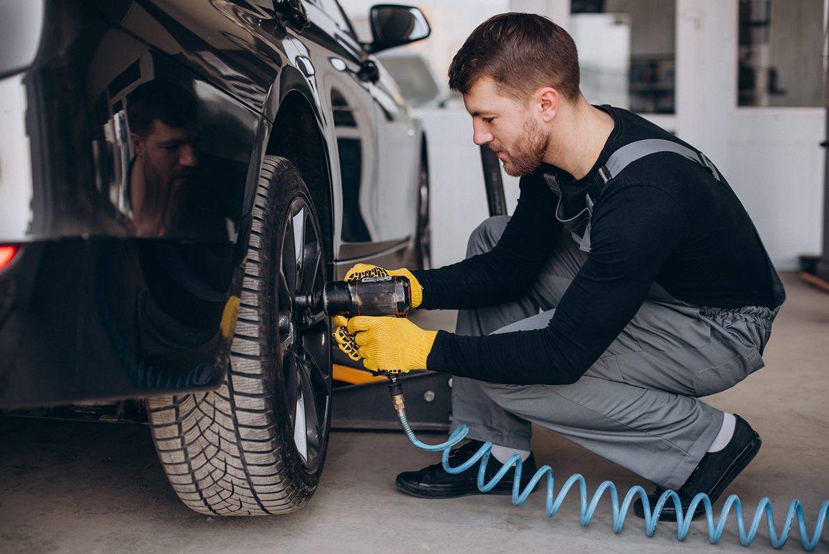 Mechanic servicing car wheel Tire & Wheel Service in garage with tools