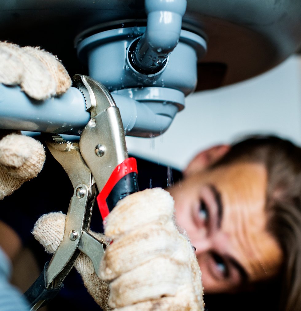 Plumber fixing pipes with a wrench, working on plumbing system.