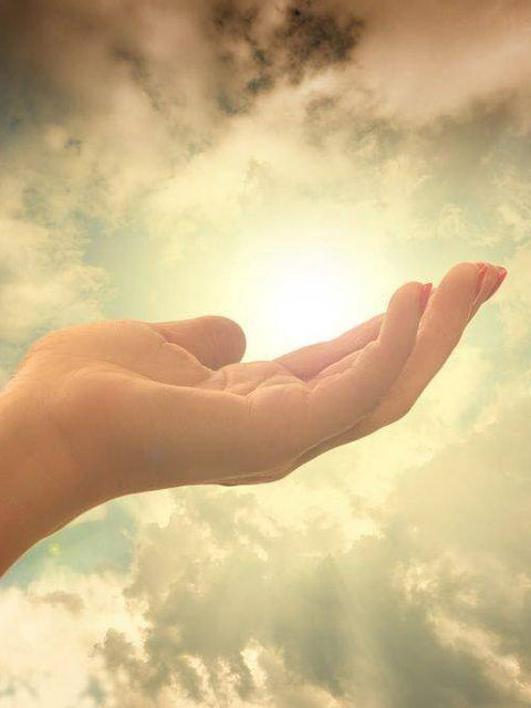Hand in front of a bright light in the sky. Faith, not giving up, and allowing yourself to receive are important ways to manifest your intentions.
