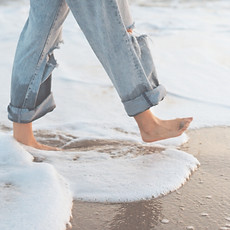 Walking barefoot on the beach, reflecting the potential for improved mobility and reduced discomfort with Craniosacral and Fu