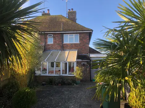 a brick house with a conservatory and a palm tree in front of it