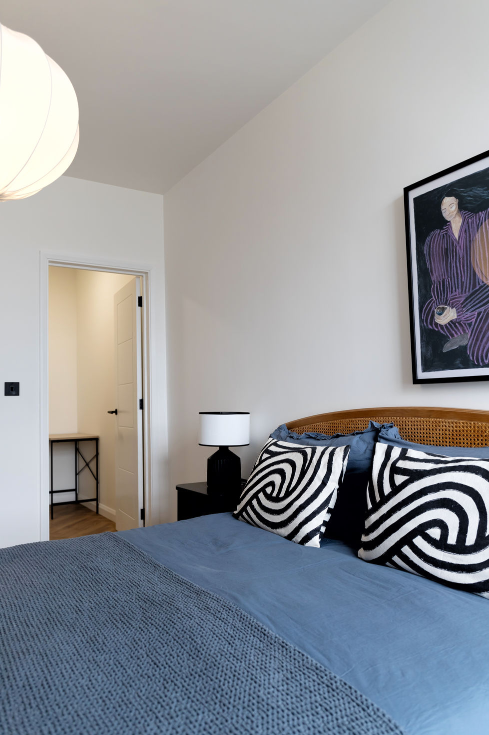 a bedroom with a painting on the wall above the bed