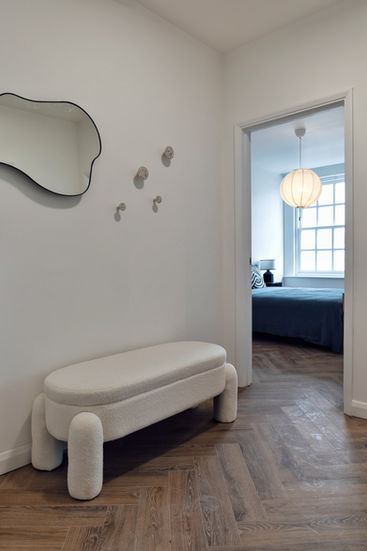 a white bench sits in a hallway next to a mirror