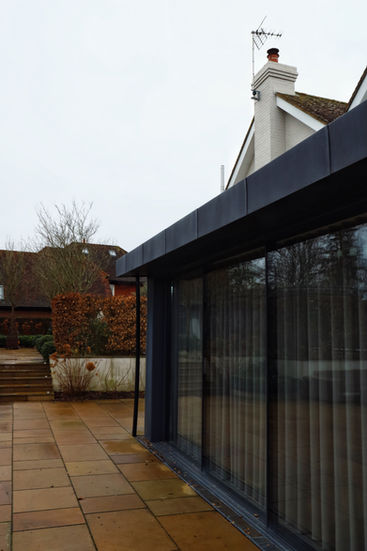 a house with a black roof and a sliding glass door