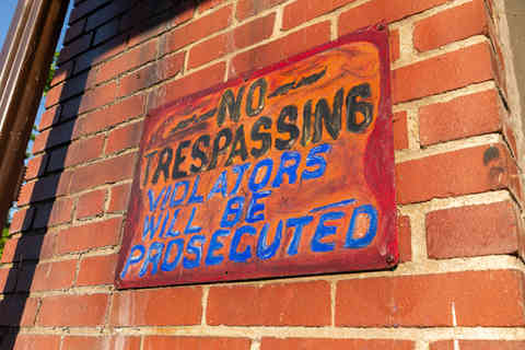 No Trespassing sign on red brick wall.